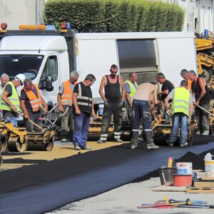 Travailleurs réparant une route avec équipement de construction.